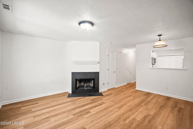 120B Tamara Ln, Port Royal, SC 29935 - unfurnished living room featuring light wood-type flooring, a textured ceiling, and a fireplace with flush hearth