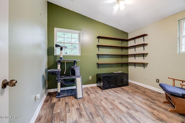 exercise room featuring wood finished floors, vaulted ceiling, and baseboards