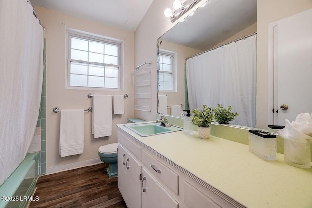 bathroom with wood finished floors, toilet, baseboards, vanity, and vaulted ceiling
