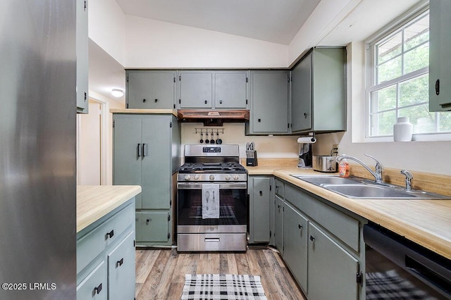 kitchen featuring stainless steel range with gas stovetop, a sink, gray cabinets, black dishwasher, and lofted ceiling