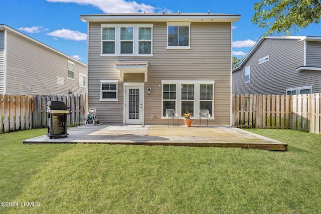 rear view of property featuring a wooden deck and a lawn