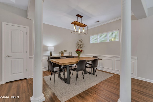 dining space featuring crown molding, dark hardwood / wood-style floors, an inviting chandelier, and ornate columns