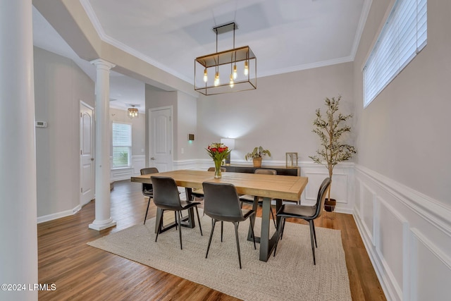 dining area featuring hardwood / wood-style flooring, ornamental molding, and ornate columns