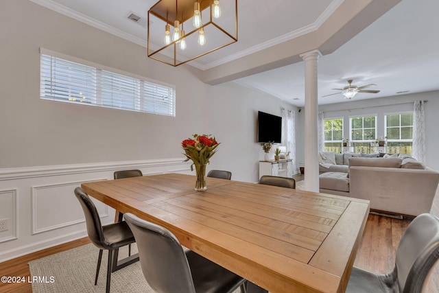 dining space with hardwood / wood-style floors, ornamental molding, ceiling fan, and ornate columns