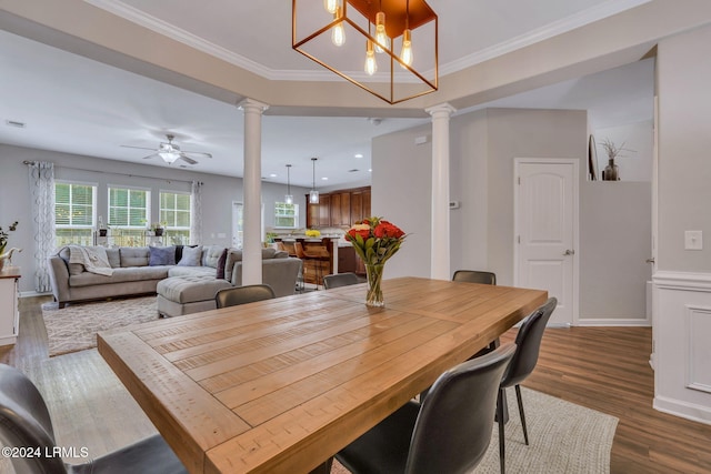 dining room with ornate columns, crown molding, dark wood-type flooring, and ceiling fan