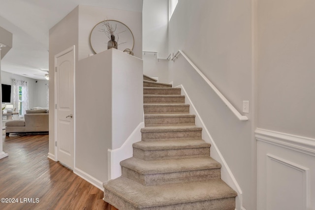 stairs with hardwood / wood-style floors and ceiling fan