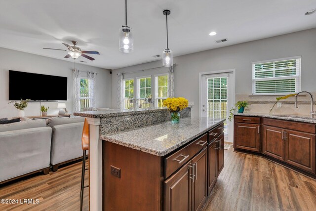 living room with ceiling fan, sink, decorative columns, and light hardwood / wood-style flooring