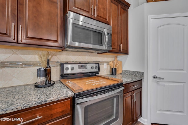 kitchen with light stone counters, appliances with stainless steel finishes, and backsplash