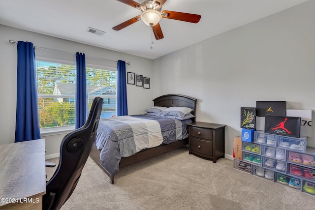 bedroom with multiple windows, ceiling fan, and light carpet