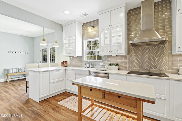 39 Barrington Ave, Bluffton, SC 29910 - kitchen with black electric cooktop, a breakfast bar area, visible vents, wall chimney range hood, and a peninsula