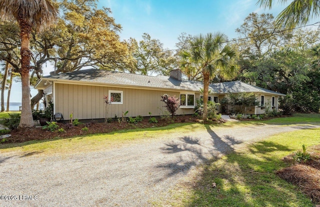 view of front facade featuring driveway, a chimney, and a front yard