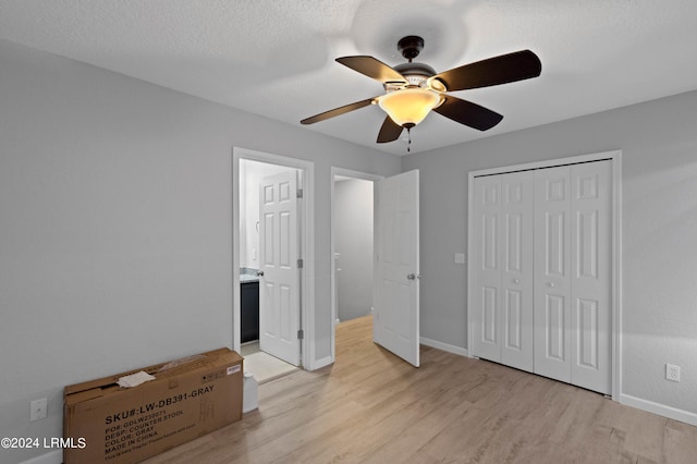 unfurnished bedroom with a textured ceiling, light hardwood / wood-style flooring, a closet, and ceiling fan