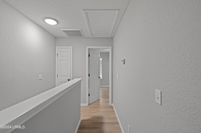 hall featuring a textured ceiling and light hardwood / wood-style floors