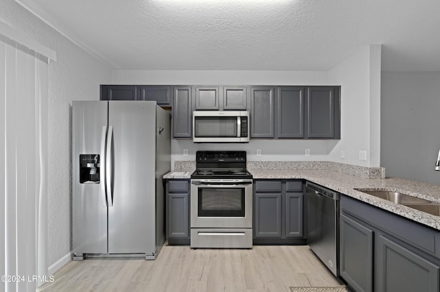 kitchen featuring sink, gray cabinets, stainless steel appliances, and a textured ceiling