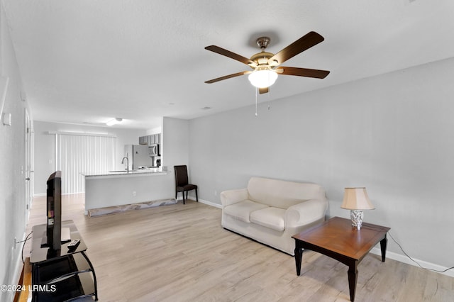 living room featuring ceiling fan, sink, and light hardwood / wood-style flooring