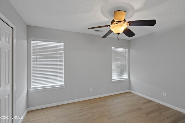 empty room with ceiling fan and light hardwood / wood-style floors