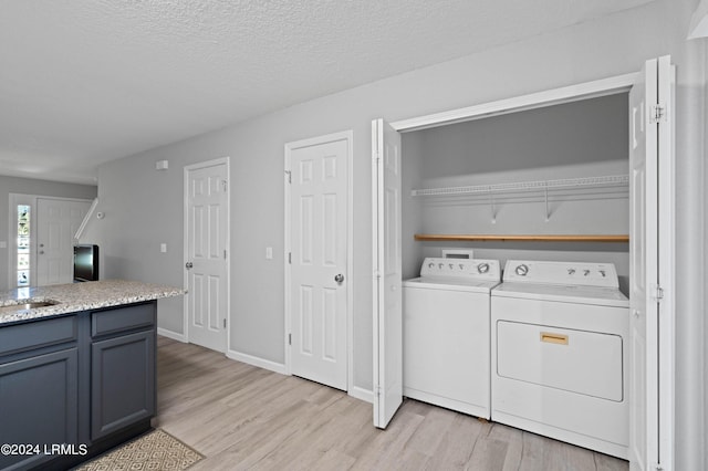 laundry area featuring washer and clothes dryer, light hardwood / wood-style floors, and a textured ceiling