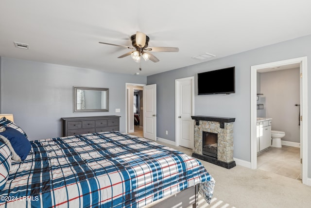 carpeted bedroom with connected bathroom, a fireplace, and ceiling fan