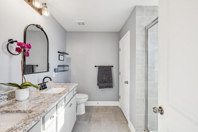 bathroom featuring a shower with door, vanity, tile patterned flooring, and toilet