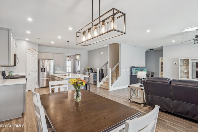 dining area with ceiling fan, sink, and light hardwood / wood-style flooring