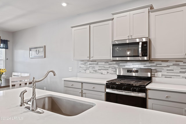 kitchen featuring tasteful backsplash, stainless steel appliances, gray cabinets, and sink