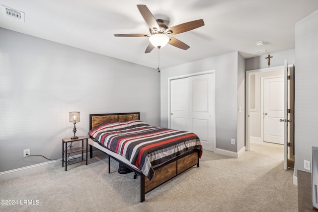 bedroom with light carpet, ceiling fan, and a closet