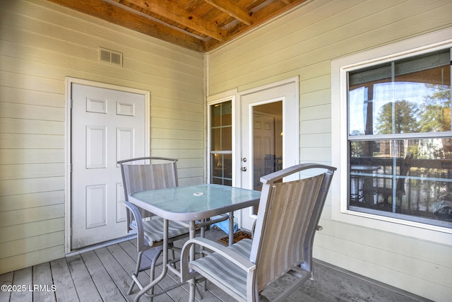 wooden terrace with outdoor dining area and visible vents