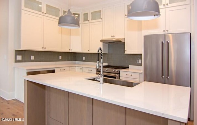 kitchen featuring pendant lighting, white cabinetry, light hardwood / wood-style floors, an island with sink, and high end refrigerator