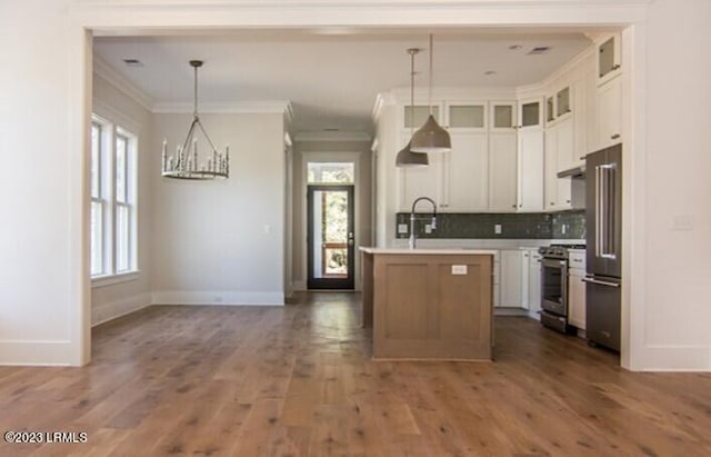 kitchen with pendant lighting, white cabinetry, stainless steel appliances, dark hardwood / wood-style floors, and a center island with sink