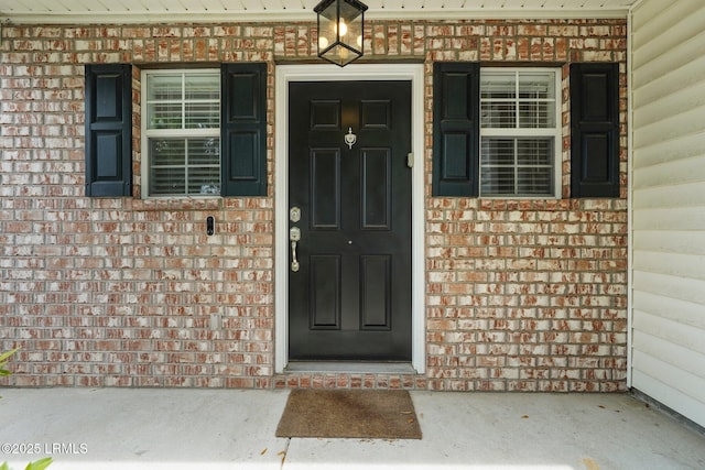 property entrance featuring covered porch and brick siding