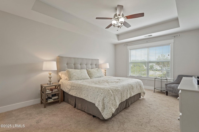 bedroom with baseboards, visible vents, a raised ceiling, and light carpet