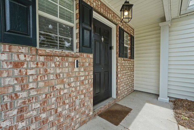entrance to property with brick siding and a porch