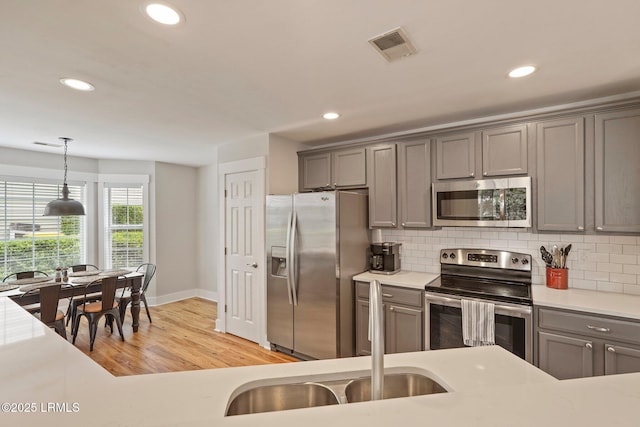 kitchen featuring gray cabinets, stainless steel appliances, recessed lighting, and a sink