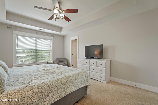 bedroom featuring visible vents, ceiling fan, a tray ceiling, baseboards, and light carpet