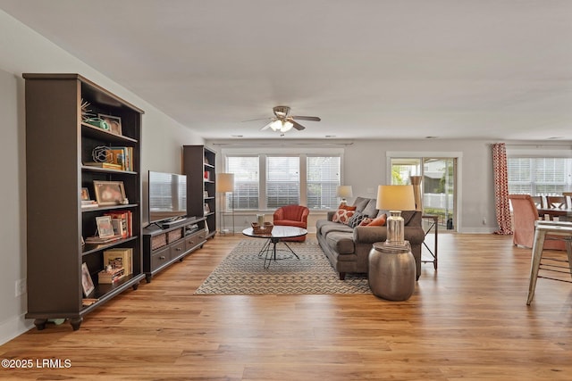 living room featuring ceiling fan, baseboards, and light wood-style floors