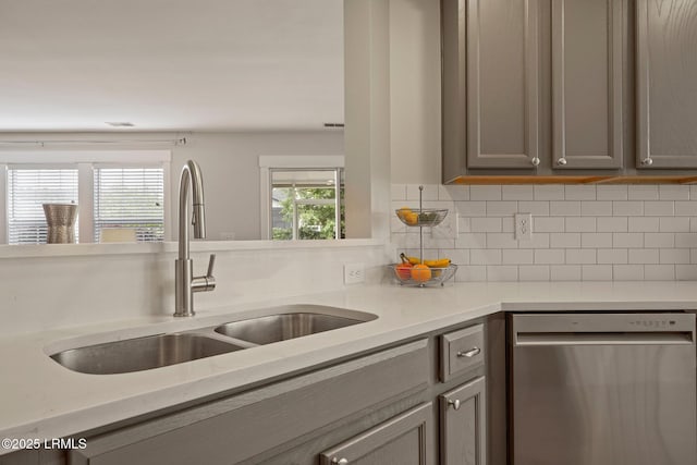 kitchen featuring gray cabinets, plenty of natural light, dishwasher, and a sink