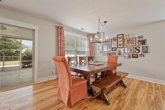 dining area with baseboards, an inviting chandelier, and light wood finished floors