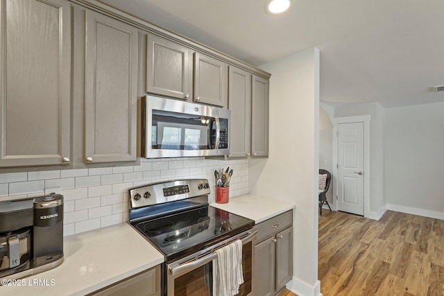 kitchen with gray cabinets, stainless steel appliances, backsplash, and light countertops