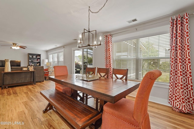 dining room with visible vents, light wood-type flooring, ceiling fan with notable chandelier, and baseboards