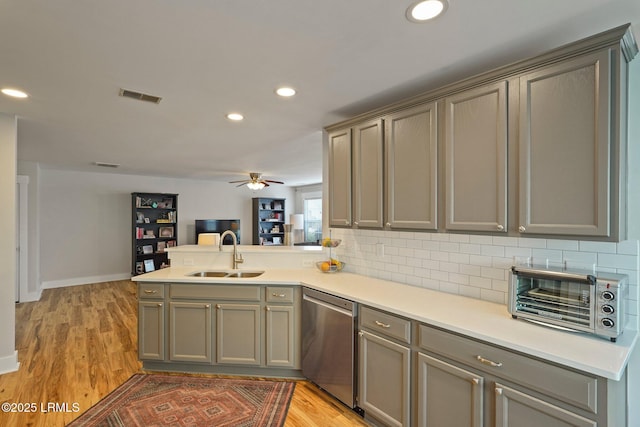 kitchen featuring stainless steel dishwasher, a sink, visible vents, a toaster, and gray cabinets