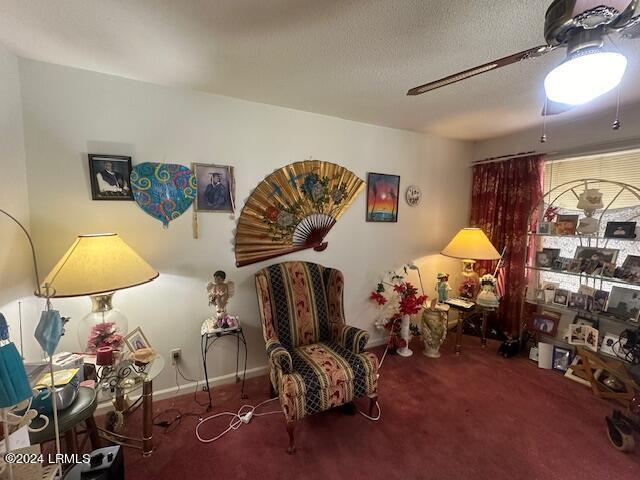 sitting room featuring ceiling fan, a textured ceiling, and dark colored carpet