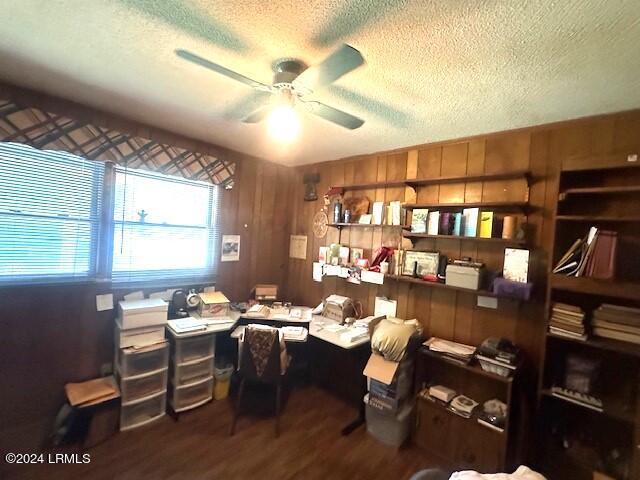 office area featuring ceiling fan, hardwood / wood-style floors, a textured ceiling, and wooden walls