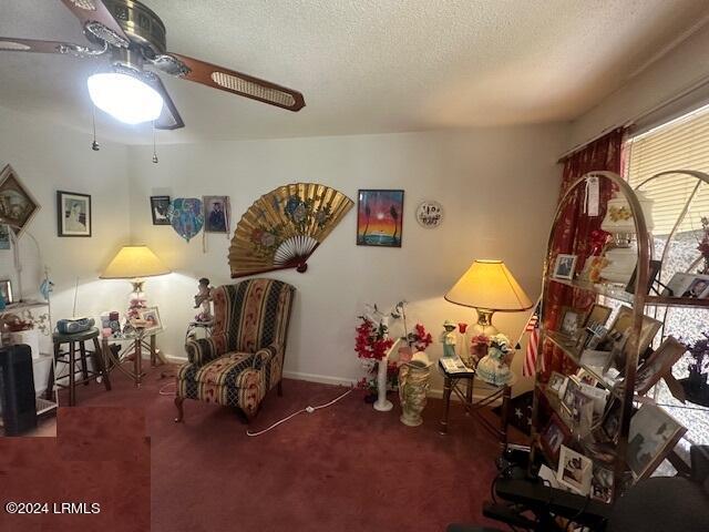 sitting room with ceiling fan, a textured ceiling, and carpet flooring