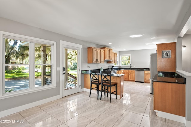 702 Center Dr W, Beaufort, SC 29902 - kitchen with stainless steel appliances, a peninsula, dark countertops, baseboards, and a kitchen bar