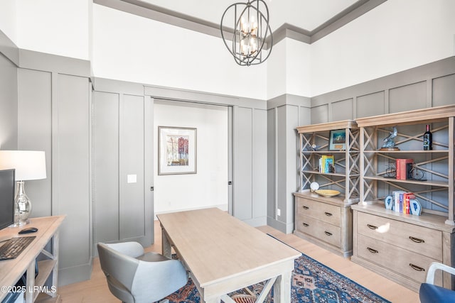 home office with light wood-style floors, a chandelier, a wainscoted wall, and a decorative wall