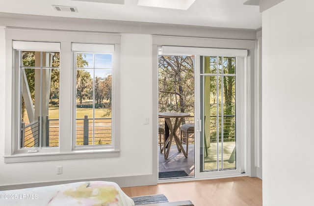 doorway featuring visible vents, plenty of natural light, and wood finished floors