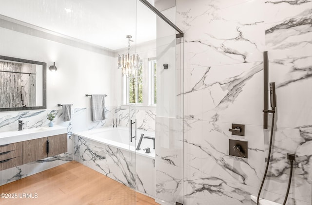 bathroom with a chandelier, a marble finish shower, a bath, and vanity