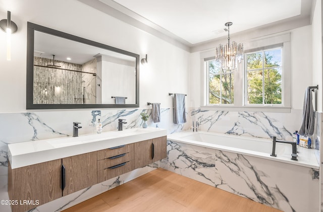 full bathroom with a notable chandelier, double vanity, a marble finish shower, wood finished floors, and a bath
