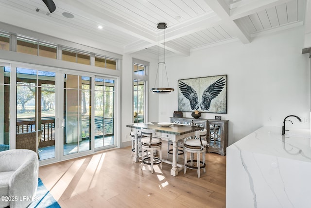 dining space featuring beam ceiling, a healthy amount of sunlight, and light wood-type flooring