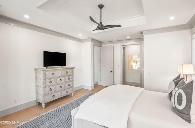 bedroom featuring light wood-type flooring, recessed lighting, baseboards, and a tray ceiling